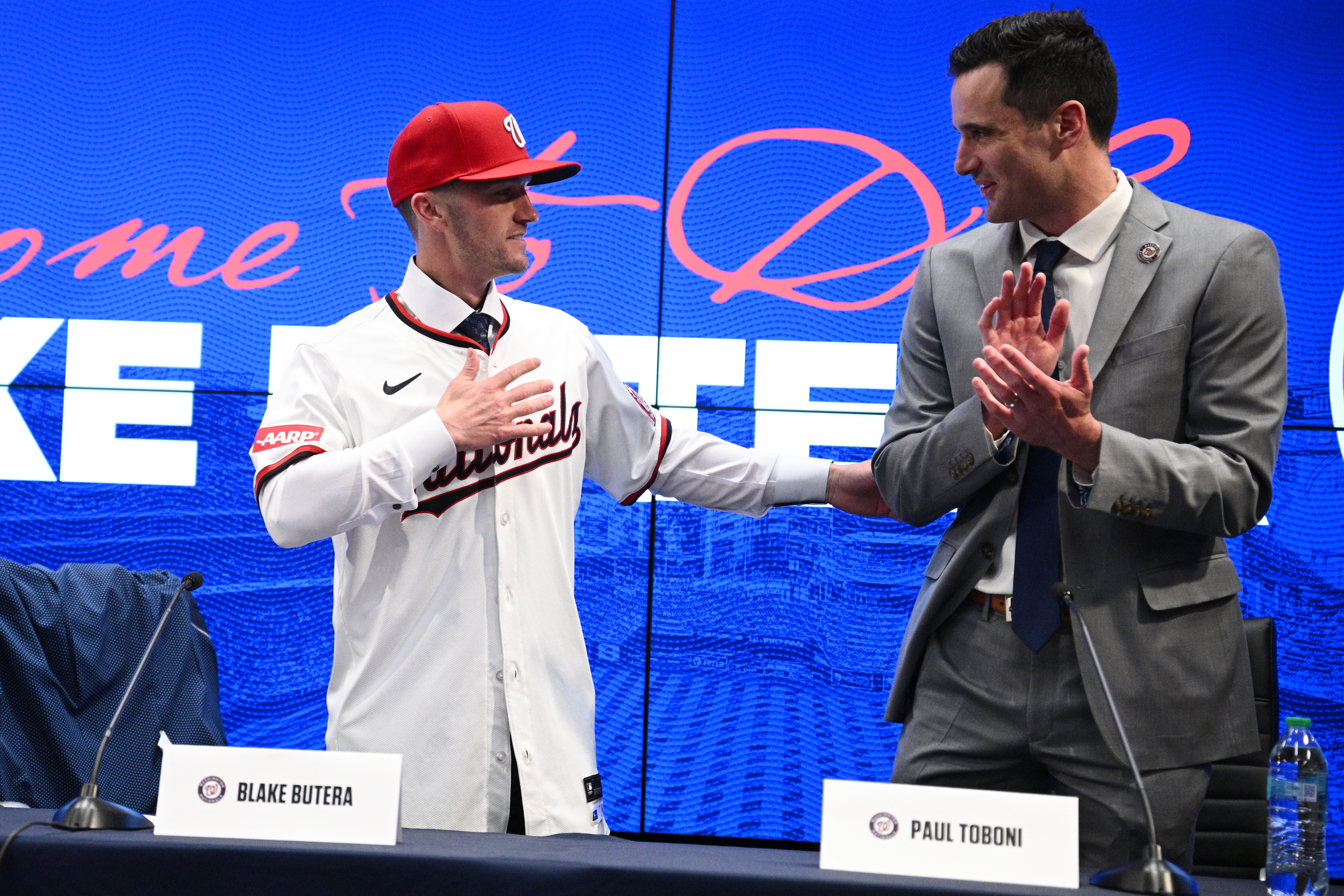 New Washington Nationals Manager Blake Butera, left, and president of baseball Operations, Paul Toboni, right, react at a baseball press conference Monday, Nov. 17, 2025, in Washington. (AP Photo/Nick Wass)