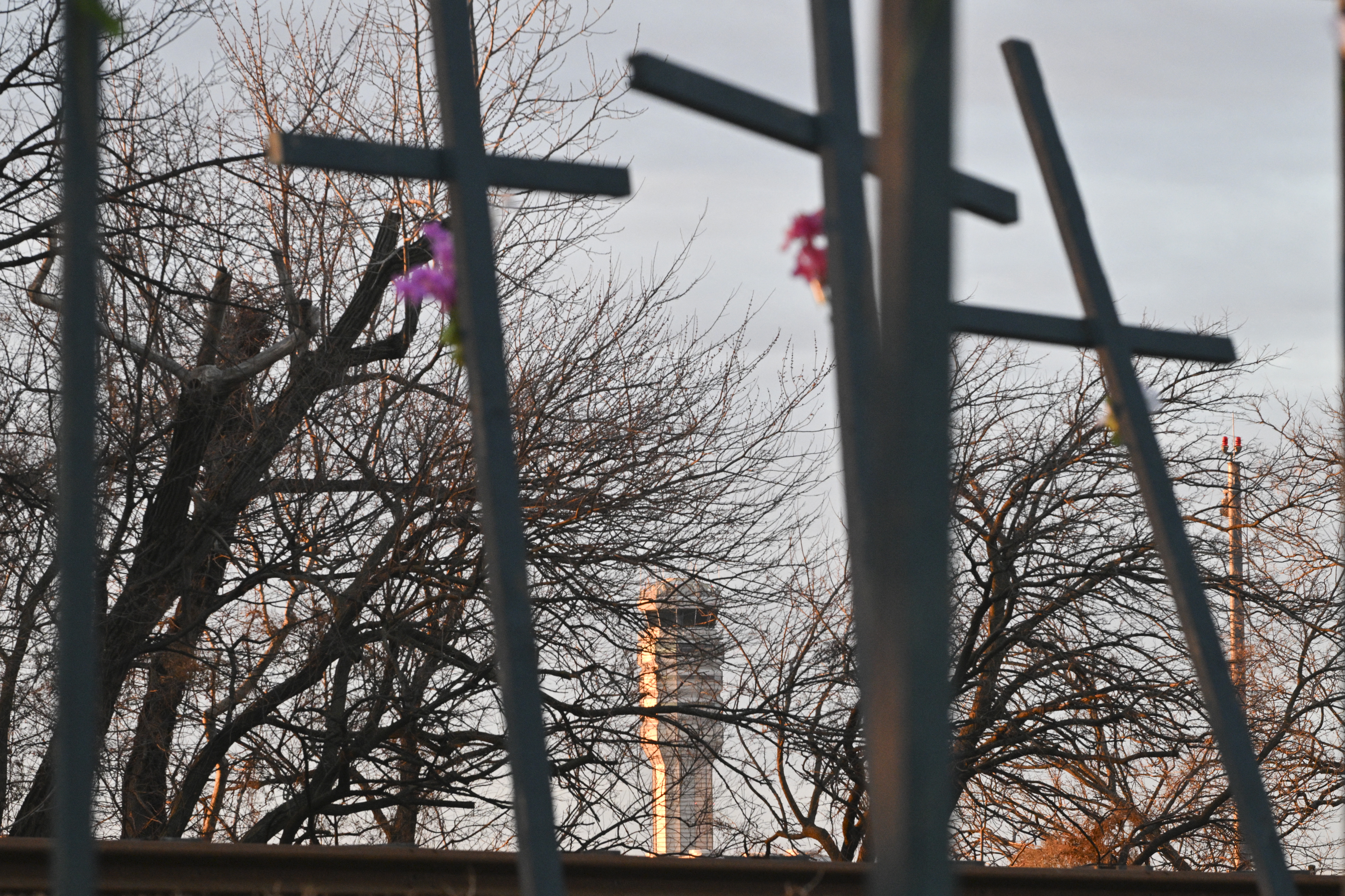 A control tower is seen behind a memorial set up in memory of the victims of a midair collision between an American Airlines flight 5342 and an Army Black Hawk helicopter, near Ronald Reagan Washington National Airport on February 2, 2025 in Arlington, Virginia. Investigators on January 30 recovered the black boxes from the plane, American Airlines flight 5342, that collided mid-air with a military helicopter over Washington's Potomac River late on January 29, killing all 67 people. (Photo by ROBERTO SCHMIDT / AFP) (Photo by ROBERTO SCHMIDT/AFP via Getty Images)          