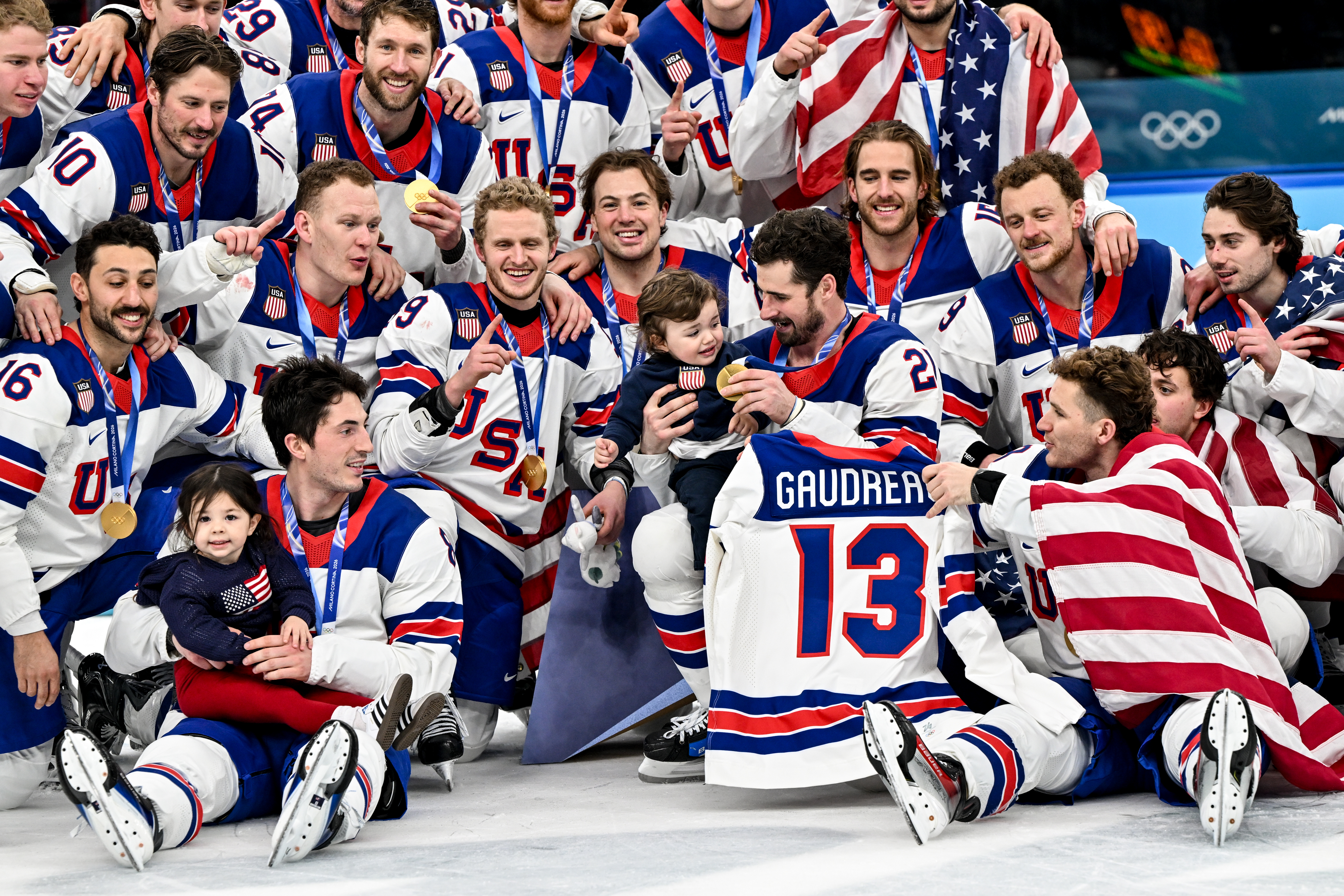 MILAN, ITALY - FEBRUARY 22: Team USA pose for a team photo with Johnny Gaudreau's children during the Ice Hockey Men's Gold Medal Game match between Canada and USA on day sixteen of the Milano Cortina 2026 Winter Olympic games at Milano Santagiulia Ice Hockey Arena on February 22, 2026 in Milan, Italy. (Photo by Andrea Branca/Eurasia Sport Images/Getty Images)