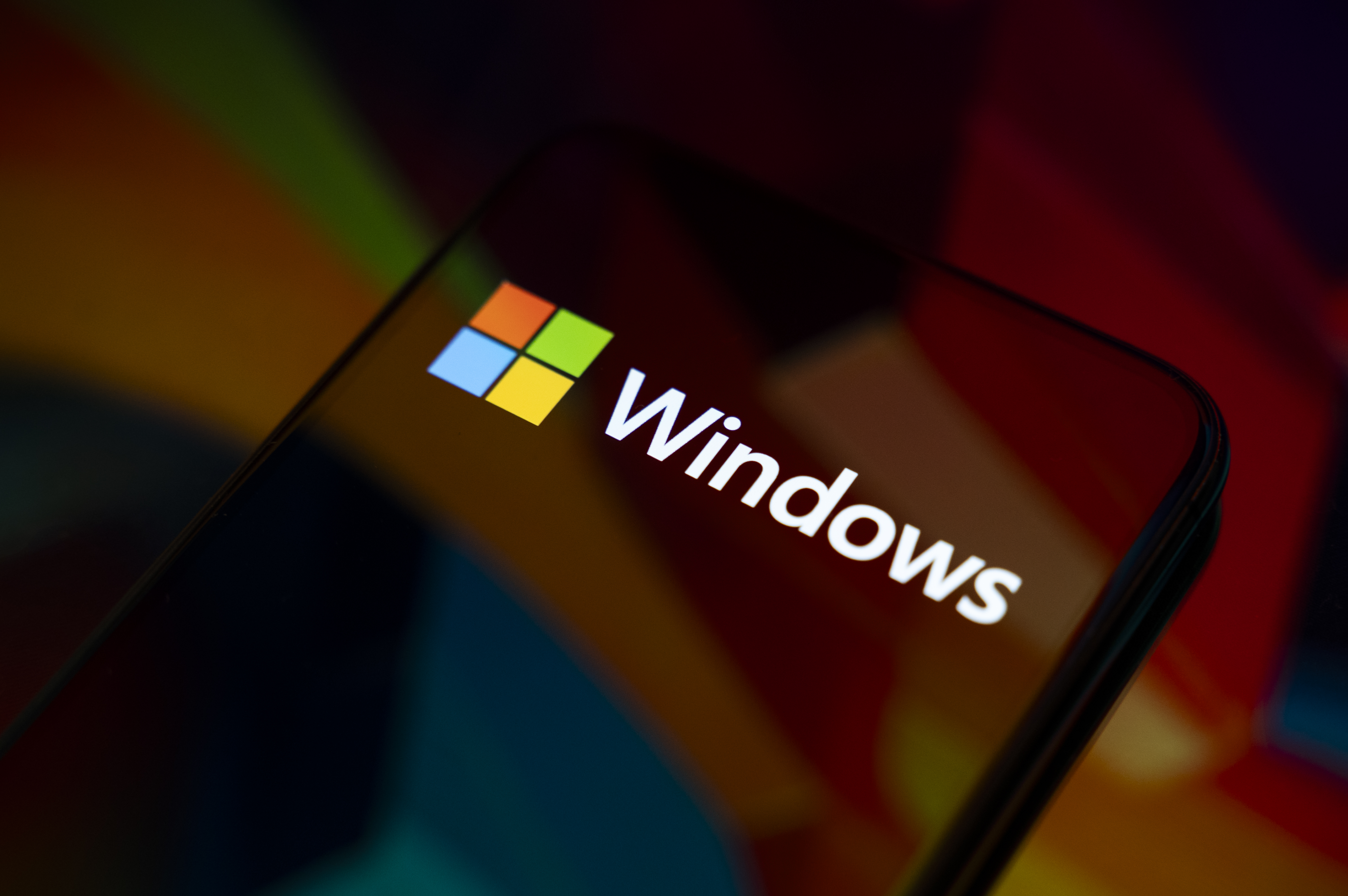 The Windows logo appears on the screen of a smartphone, which reflects an abstract illustration in Microsoft's colors of red, green, blue, and yellow. Microsoft releases a major update to Windows 11 (25H2), and support for Windows 10 ends definitively on October 14. In Creteil, France, on October 9, 2025. (Photo by Samuel Boivin/NurPhoto via Getty Images)