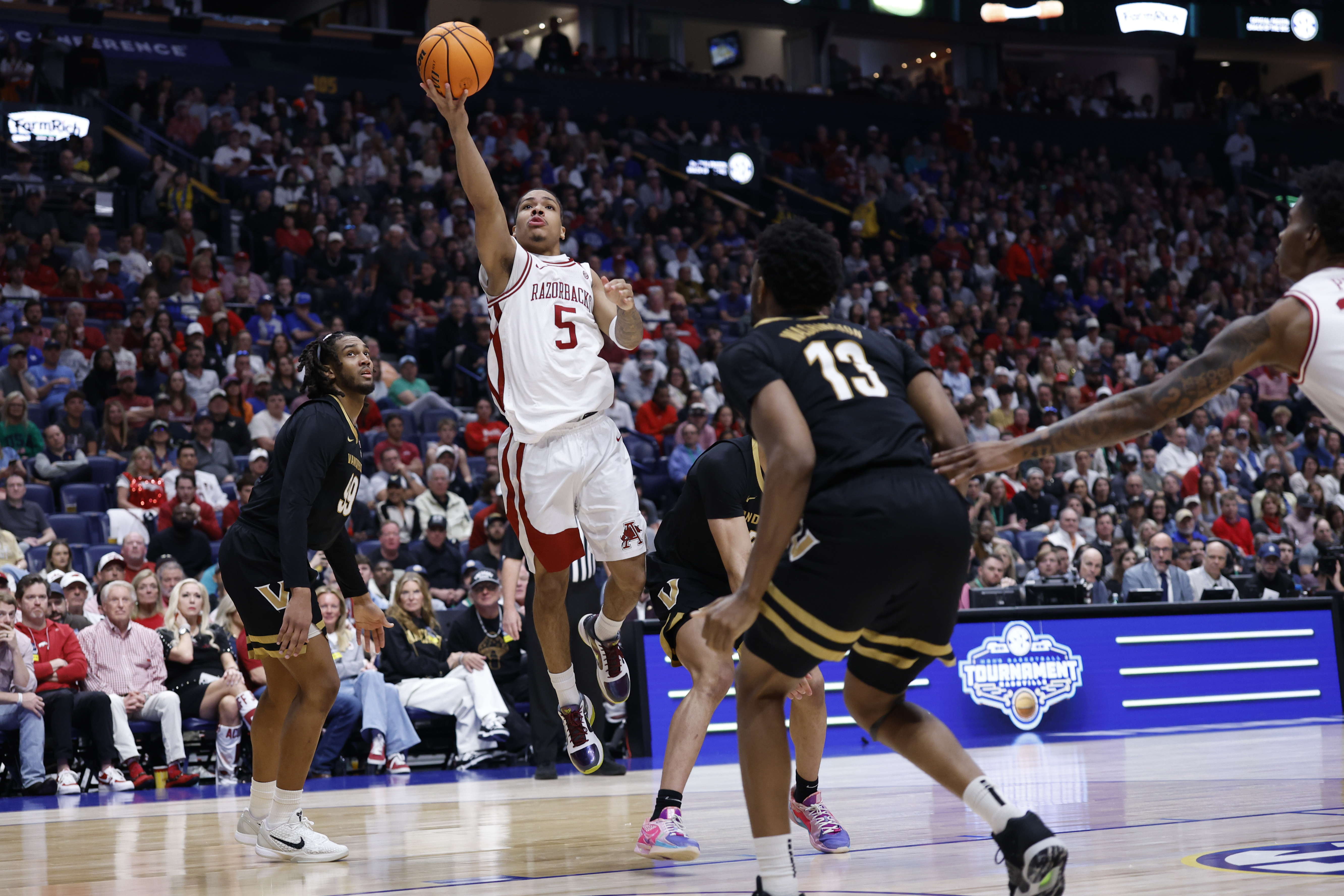 NASHVILLE, TN - MARCH 15: Arkansas Razorbacks guard Darius Acuff Jr. (5) scores on a layup between Vanderbilt Commodores forward Devin McGlockton (99) and forward Jalen Washington (13) during the SEC Tournament championship game between the Vanderbilt Commodores and Arkansas Razorbacks, March 15, 2026 at Bridgestone Arena in Nashville, Tennessee. (Photo by Matthew Maxey/Icon Sportswire via Getty Images)
