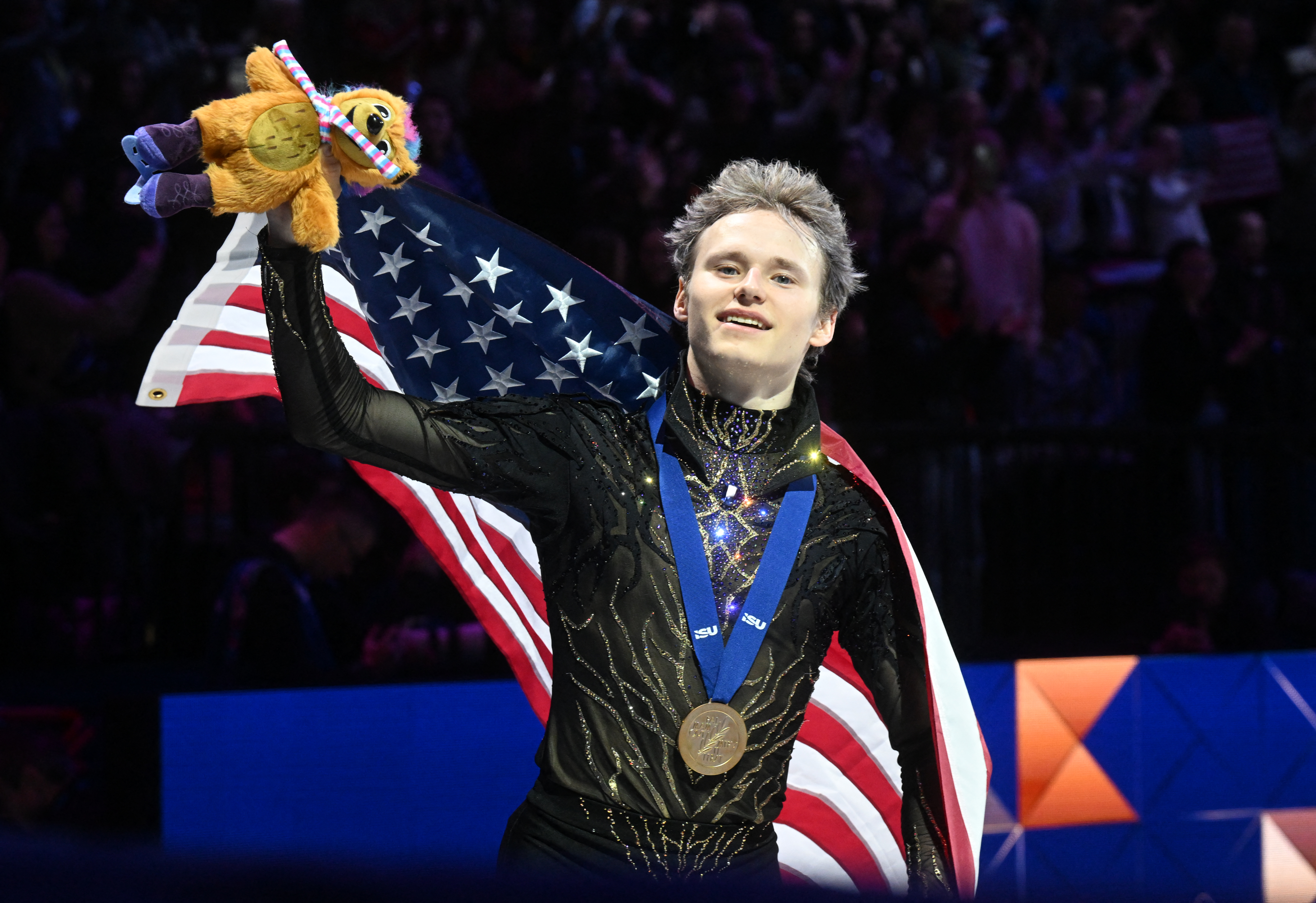 USA's Ilia Malinin celebrates with the US flag after winning the men's free skating program of the 2026 ISU Figure Skating World Championships in Prague, Czech Republic on March 28, 2026.