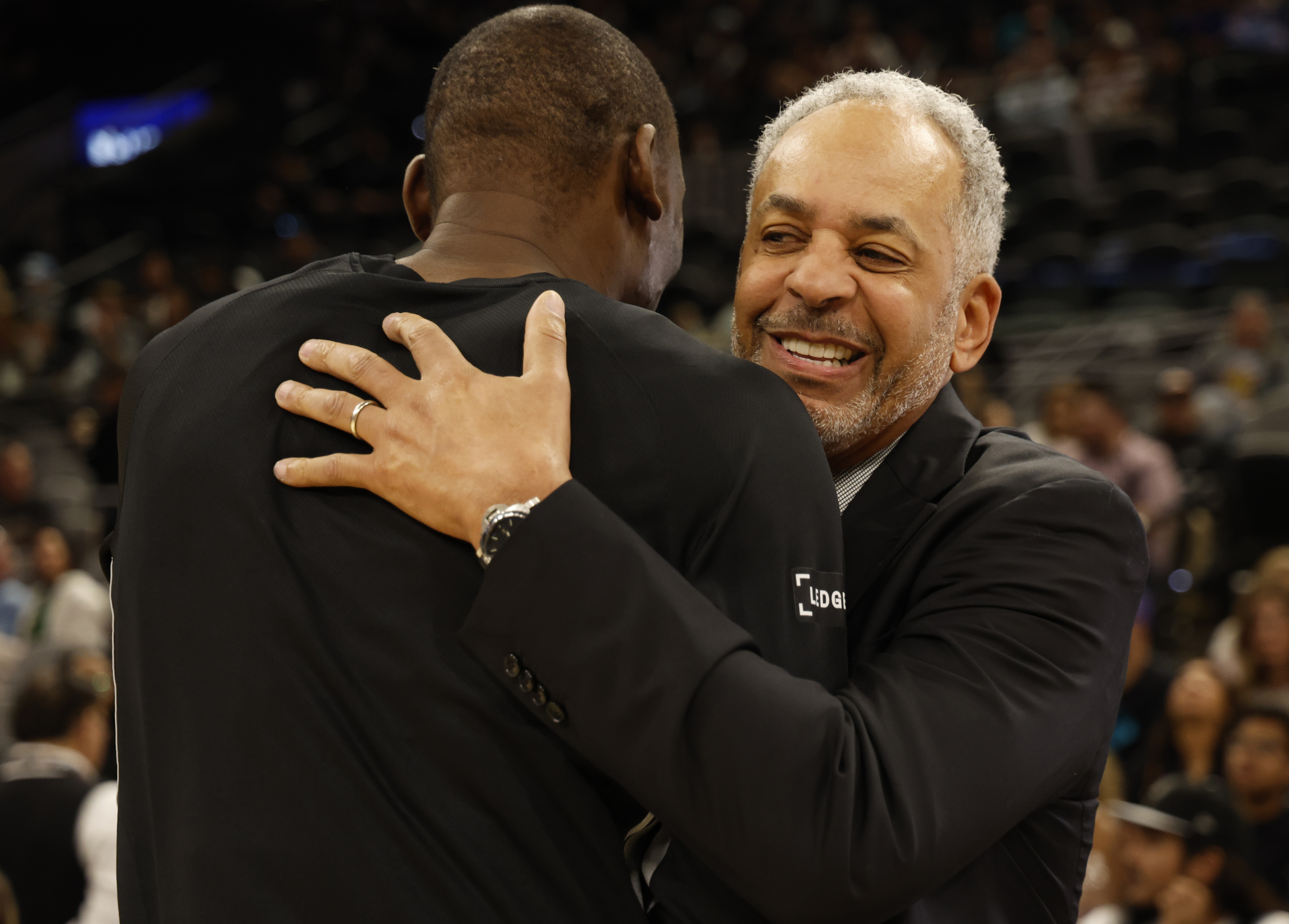 SAN ANTONIO, TX -MARCH 14: Dell Curry, prime announcer hugs Bismack Biyombo #18 of the San Antonio Spurs before the start of their game against Charlotte Hornets at Frost Bank Center on March 14, 2026 in San Antonio, Texas. NOTE TO USER: User expressly acknowledges and agrees that, by downloading and or using this photograph, User is consenting to terms and conditions of the Getty Images License Agreement. (Photo by Ronald Cortes/Getty Images)