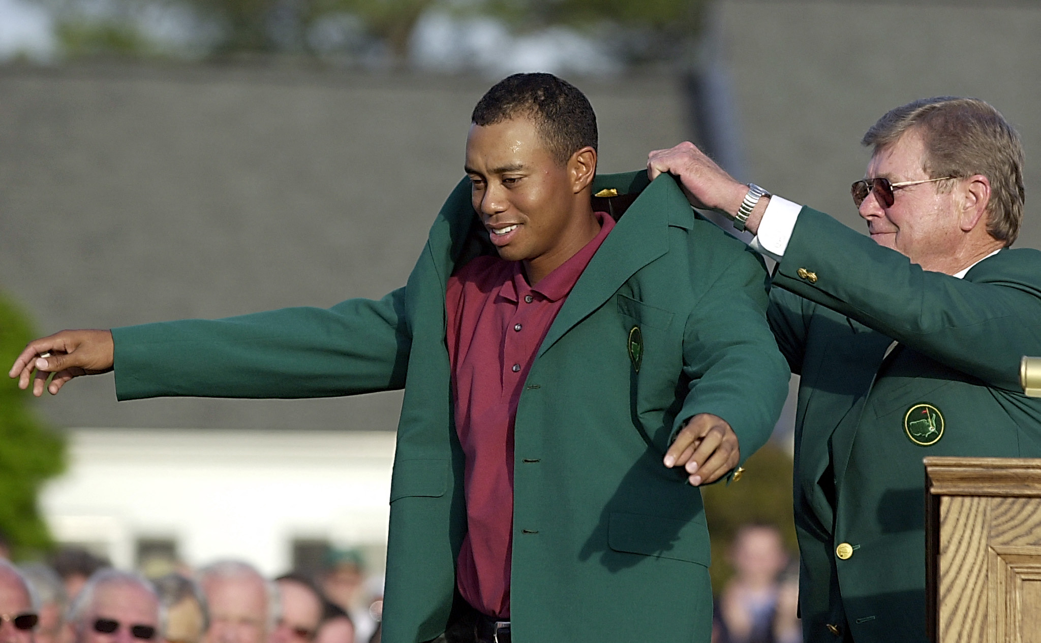 Tiger Woods (L) of the US gets his third green jacket from tournament chairman Hootie Johnson (R) 14 April 2002, after winning the 2002 Masters golf tournament at the Augusta National Golf Club in Augusta, GA. Woods finished the round one under par for a four day total of 12 under par. AFP PHOTO/ROBERTO SCHMIDT (Photo by Roberto SCHMIDT / AFP via Getty Images)