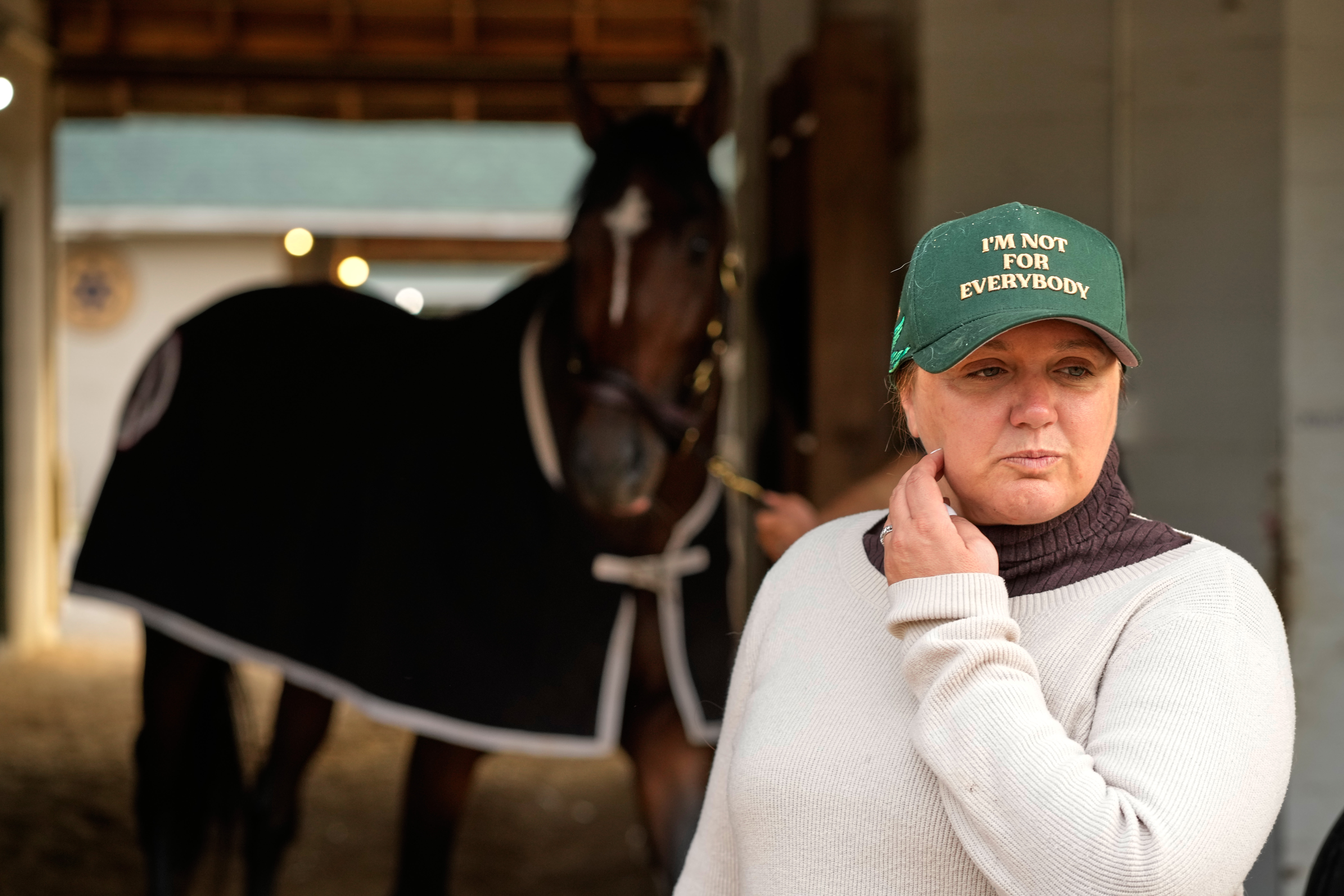 Trainer Cherie DeVaux stands watches from a barn after a workout at Churchill Downs Monday, April 27, 2026, in Louisville, Ky. (AP Photo/Charlie Riedel)