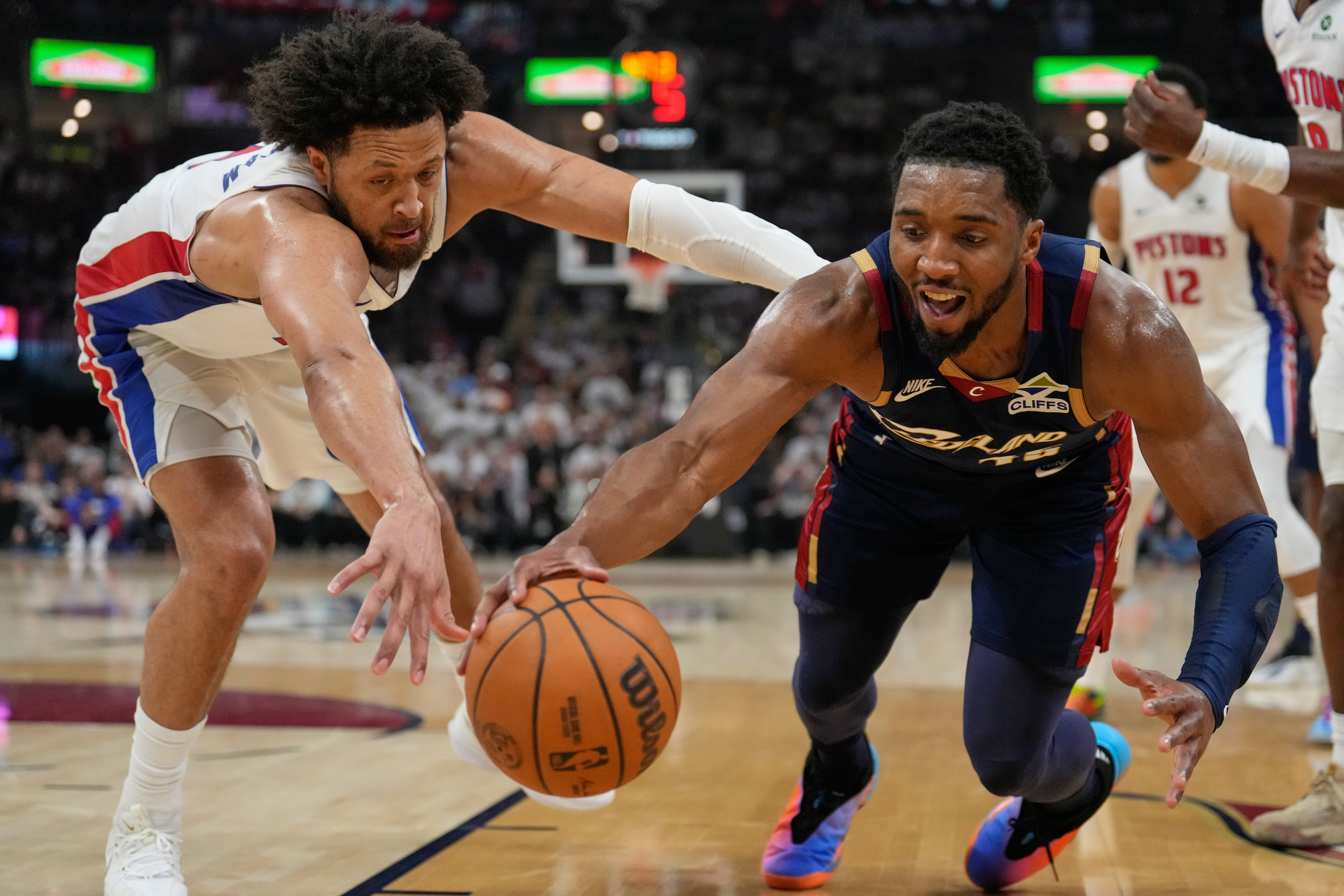 Cade Cunningham, izquierda, de los Pistons de Detroit, y Donovan Mitchell, derecha, de los Cavaliers de Cleveland, se estiran en la disputa del balón en la primera mitad del cuarto juego de la serie de segunda ronda de playoffs del baloncesto de la NBA, el lunes 11 de mao de 2026, en Cleveland. (AP Foto/Sue Ogrocki)