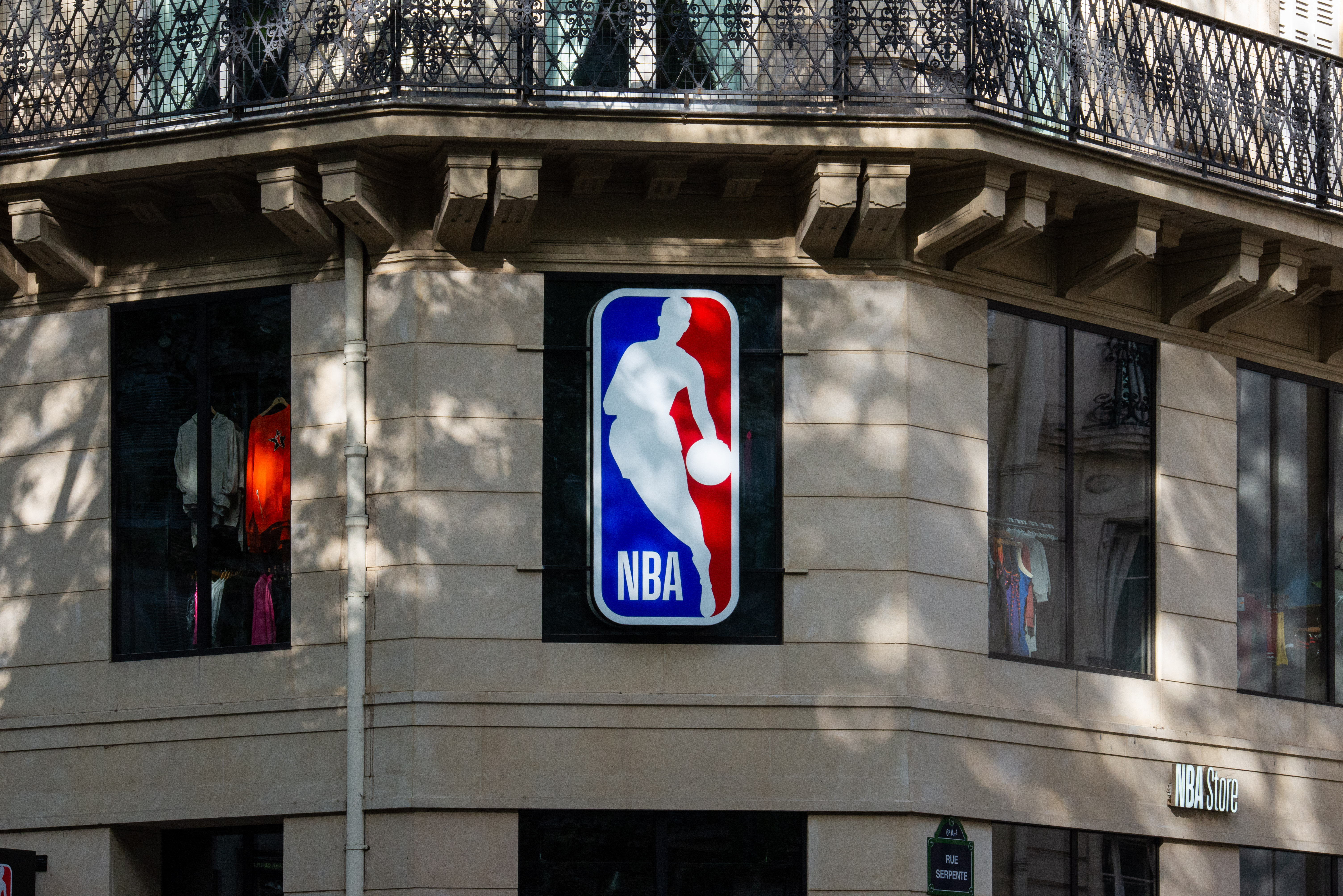 An NBA sign, featuring the iconic silhouette of the player against a blue and red background, is installed on the stone facade of a store located on Boulevard Saint-Michel in Paris, France, on May 24, 2026. Through the windows, the clothing displays evoke the world of basketball and the brand s presence in the Latin Quarter s retail landscape. (Photo by Riccardo Milani / Hans Lucas / AFP via Getty Images)