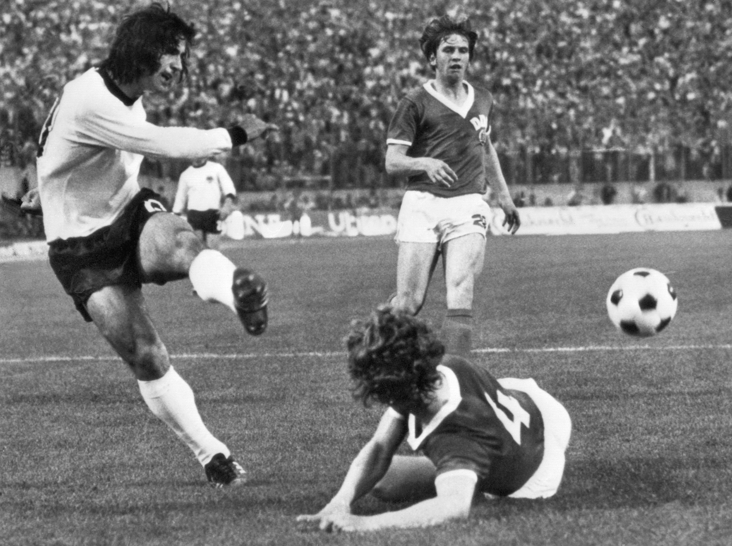 TOPSHOT - West German forward Gerd Müller kicks the ball past East German defender Konrad Weise (4) as forward Martin Hoffmann looks on during the  World Cup first round match between East Germany and West Germany 22 June 1974 in Hamburg. East Germany won 1-0 on a goal by forward Juergen Sparwasser. AFP PHOTO (Photo by AFP via Getty Images)