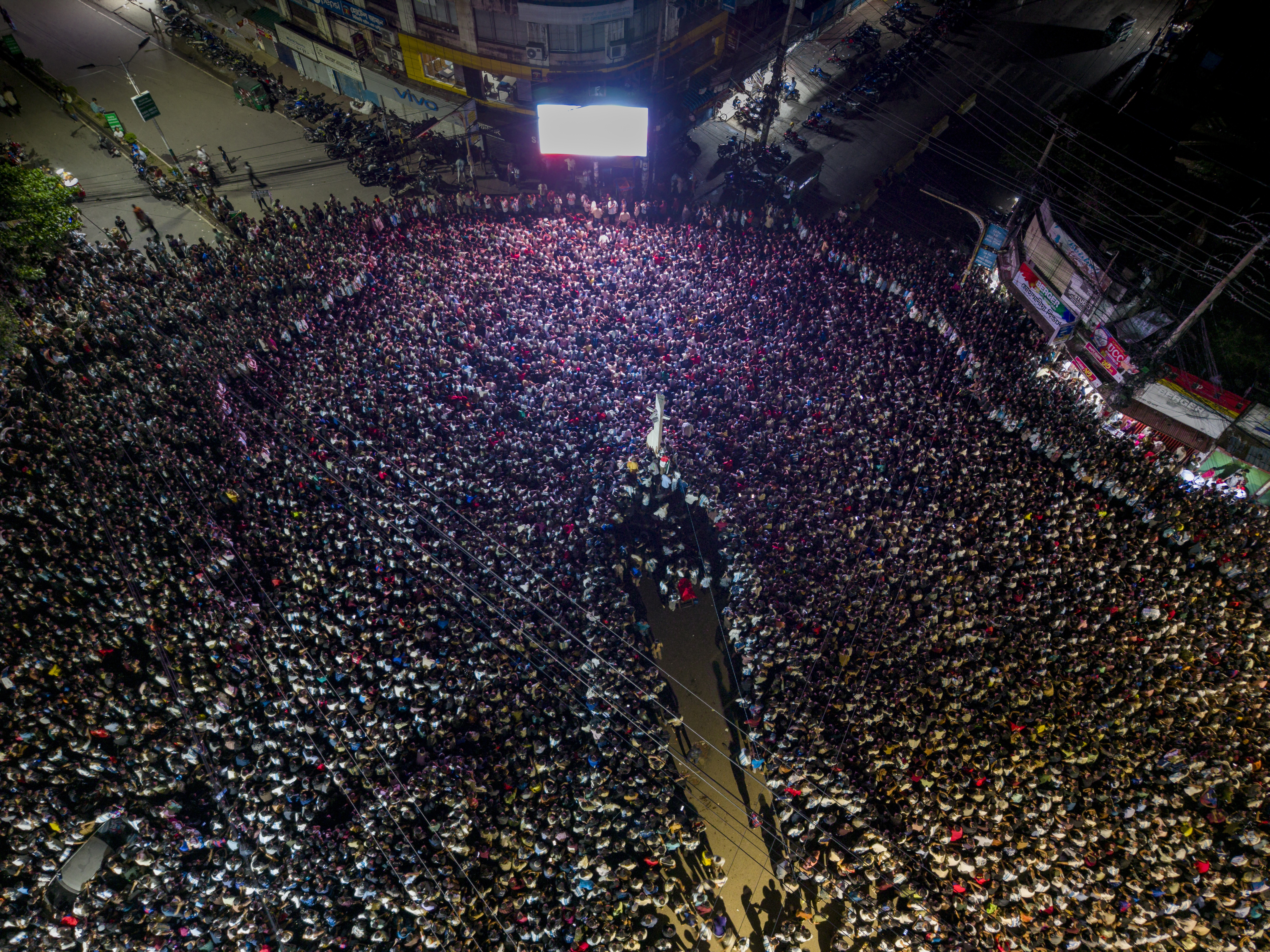 A high-altitude drone shot depicts a large crowd of people around a central city monument to view the live broadcast of the Argentina vs. Spain World Cup final in Chattogram, Bangladesh, on July 20, 2026. Chattogram's World Cup events peaked at midnight as football fans gathered at giant-screen venues, captured in bird's-eye views at CRB Shirishtala, Kazir Dewri, and No. 2 Gate. Despite Argentina's defeat to Spain, locals attended the grand finale. (Photo by Zakir Hossain/NurPhoto via Getty Images)