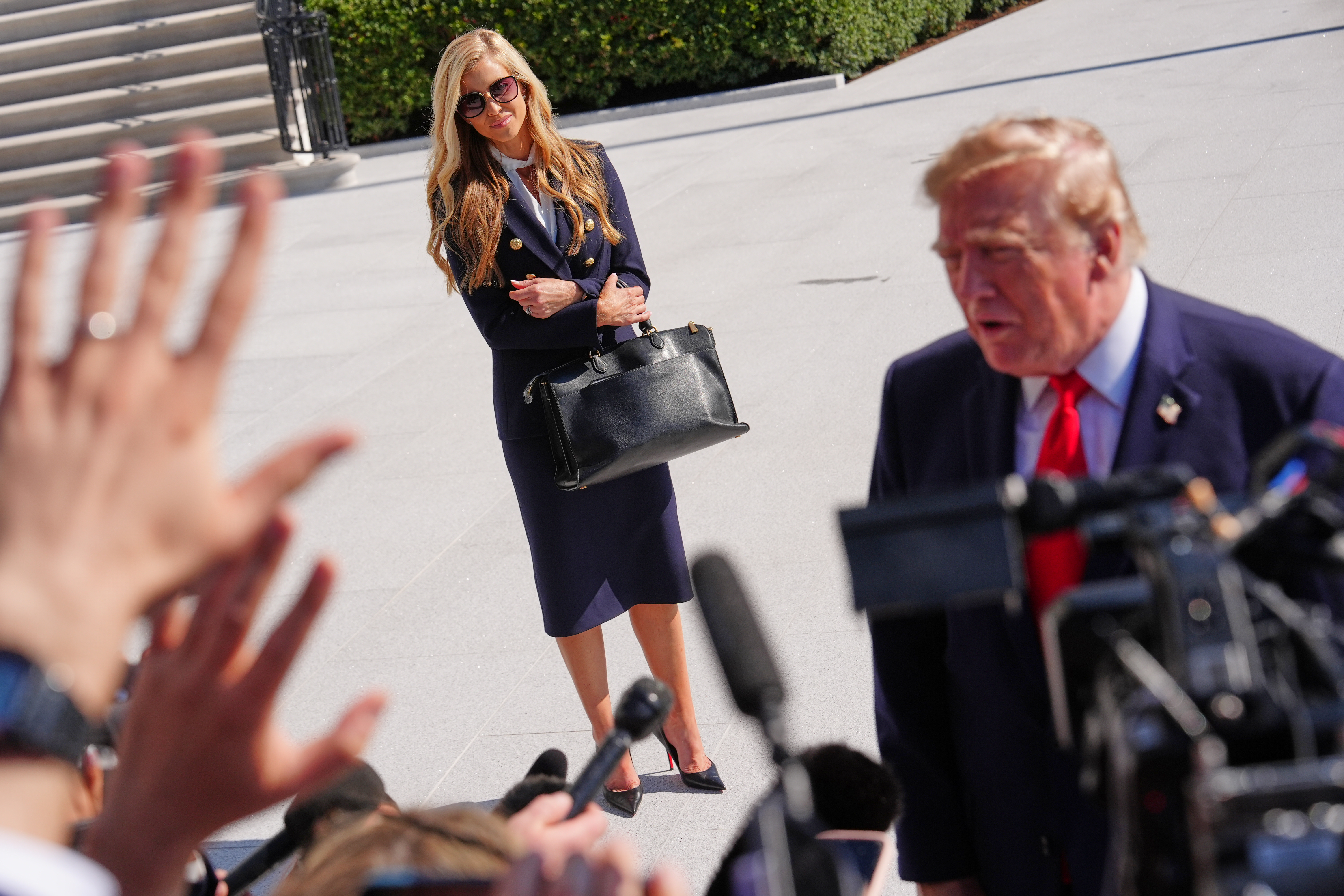 White House press secretary Katie Zacharia looks on as President  Trump speaks to reporters on the South Lawn on Oct. 13.