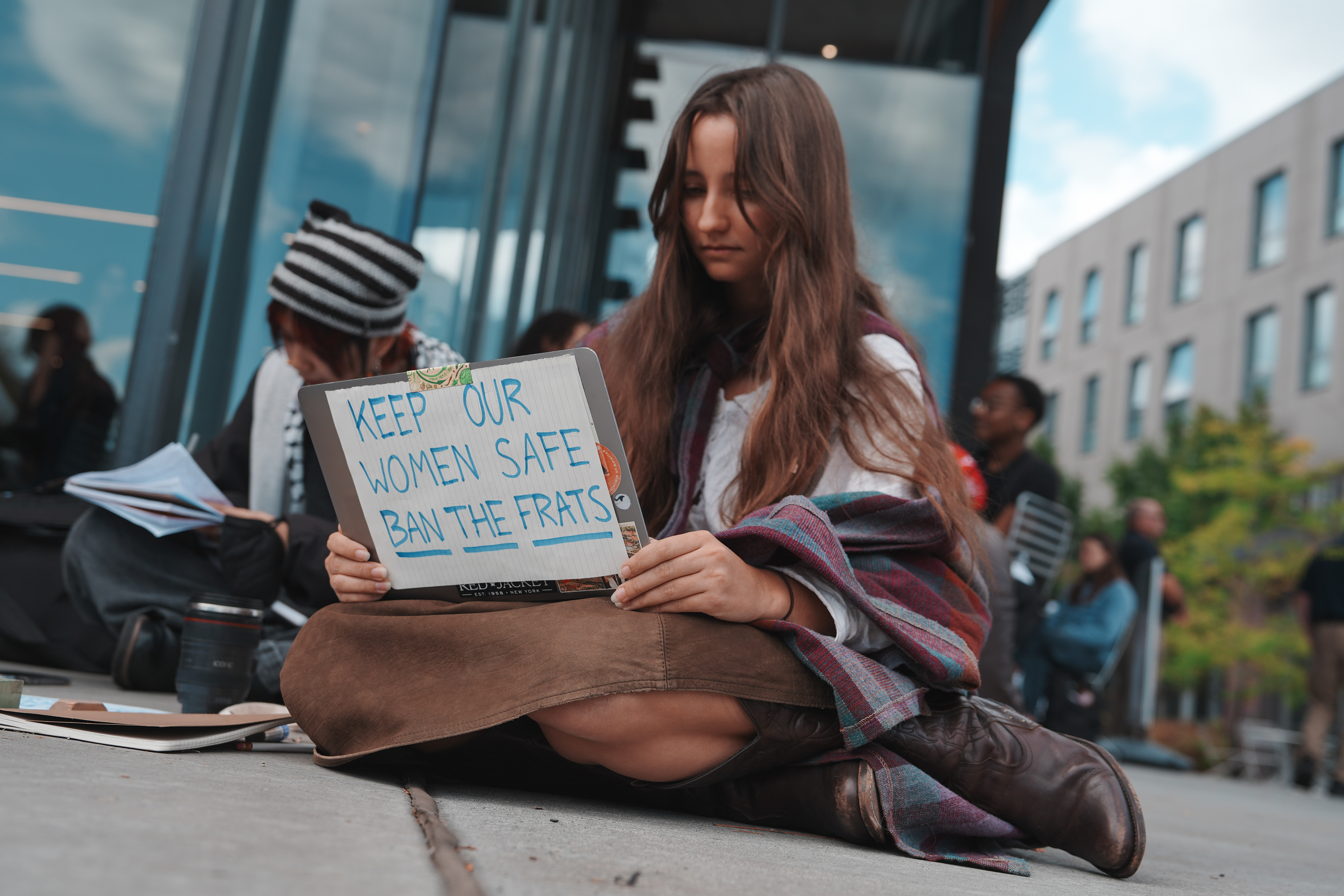 A Cornell University student sits with a sign during a campus-wide sit-in on Oct. 7.