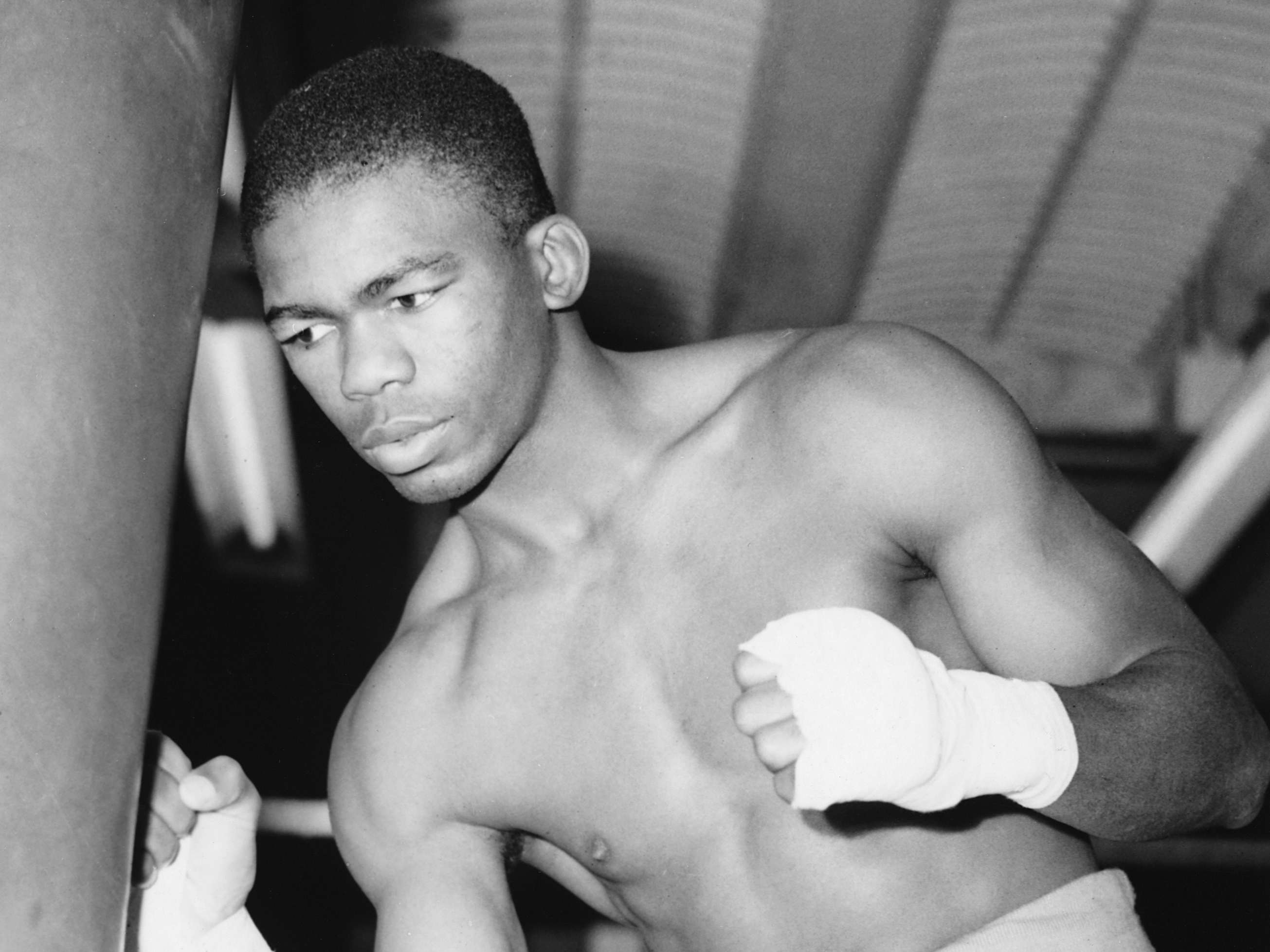 (Original Caption) Ike Williams trains for the Big Fight. Ike Williams, coloured world light-weight champion, hopes to slap down Ronnie James, the British champion when they meet for the world title at Cardiff on Wednseday, and here he is in training at Solomon's Gym, London. Photo shows: Ike at the punch-bag during training at Solomon's Gym today. (Photo by © Hulton-Deutsch Collection/CORBIS/Corbis via Getty Images)