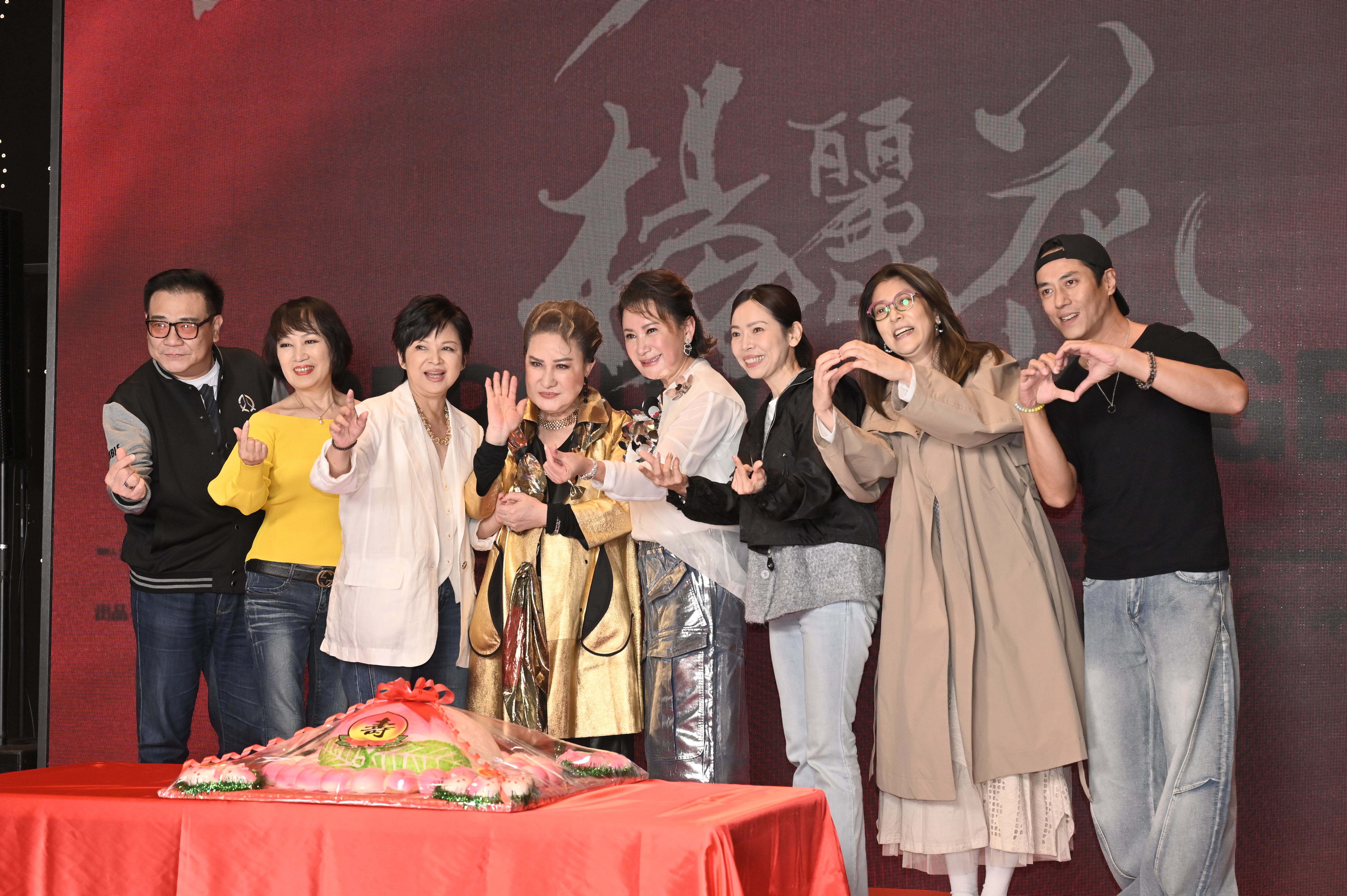 映画『世紀初戀 楊麗花』のロゴを背に、金色の衣装を着た楊麗花と友人らが誕生日の寿桃を囲む