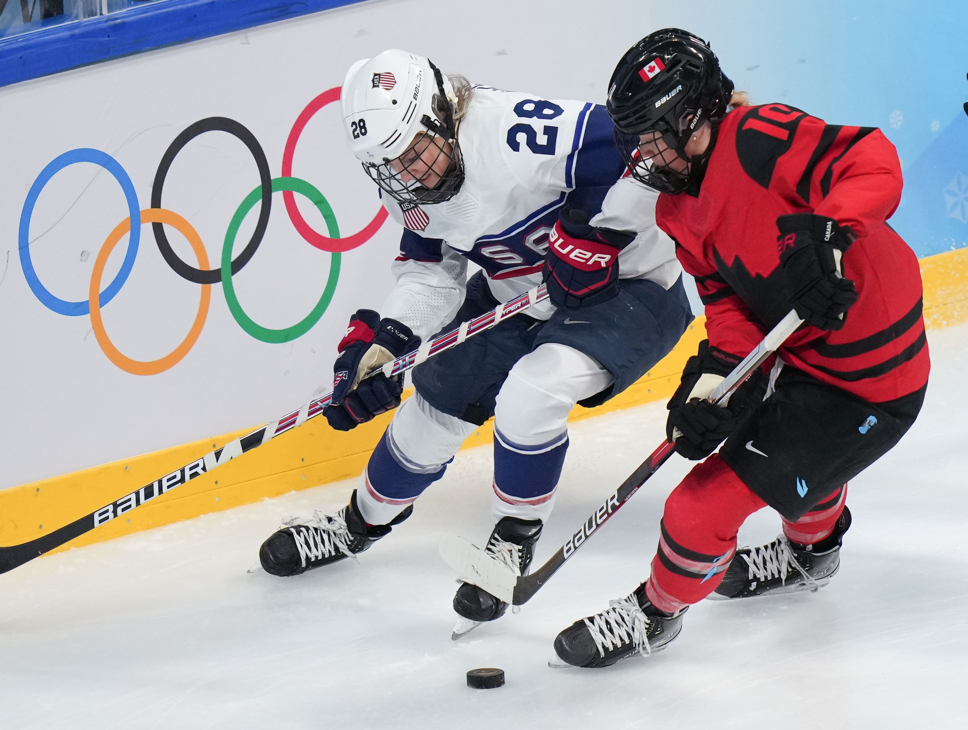 An American and Canadian player fight for the puck during 2022's gold-medal match. (Meng Yongmin/Xinhua via Getty Images)