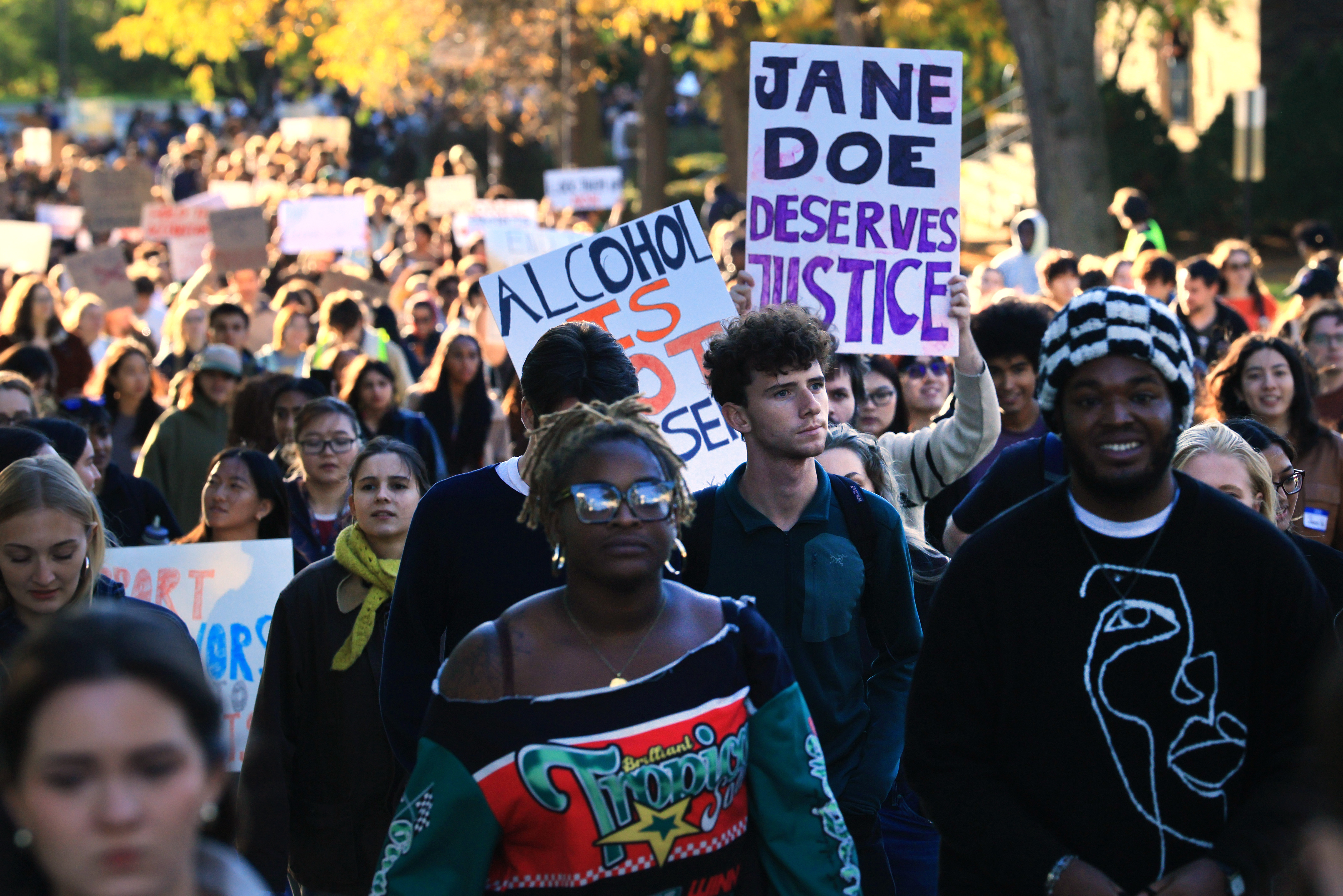 Hundreds of Cornell students participate in a rally. One holds up a sign that reads: Jane Doe deserves justice.