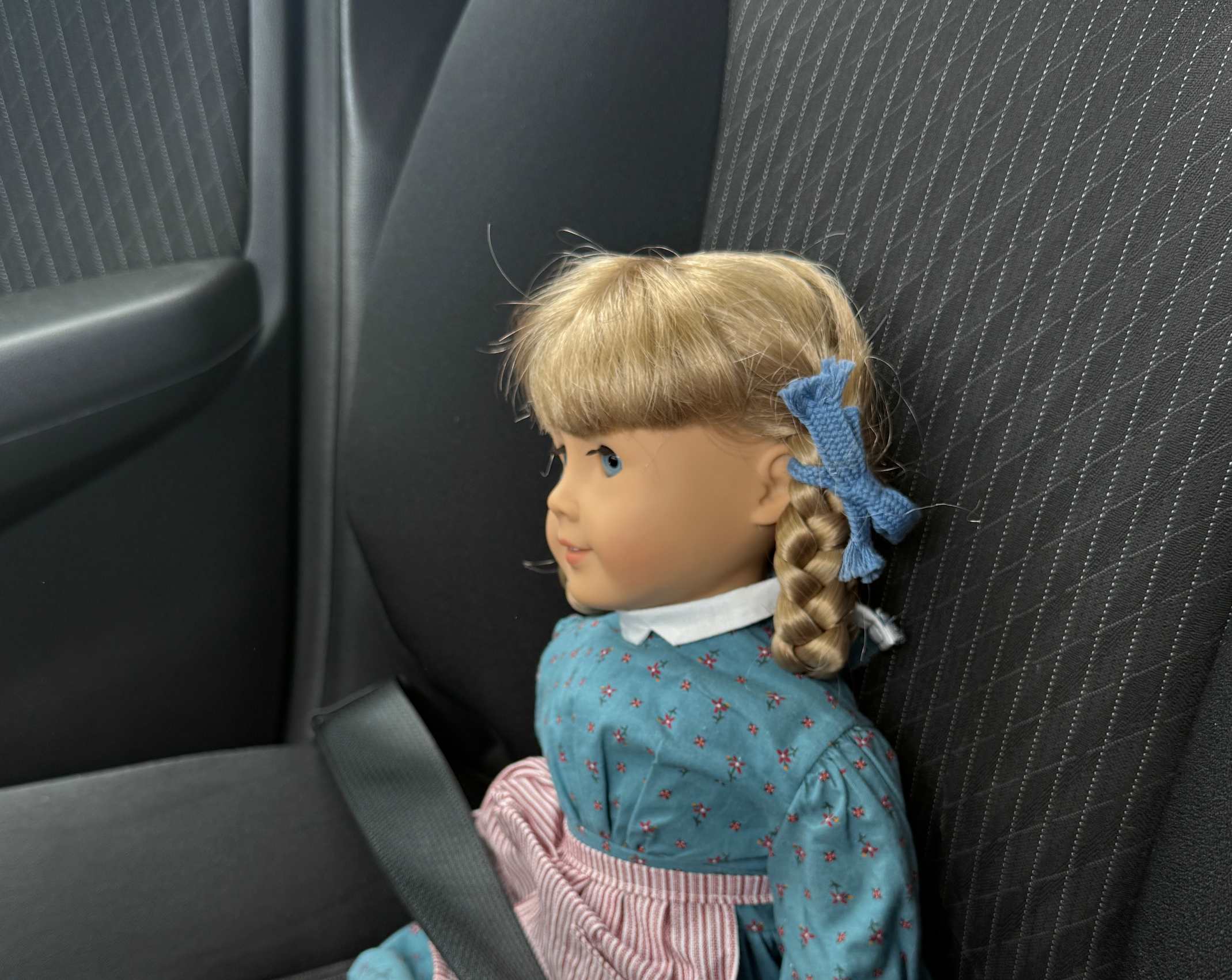 A doll in the seat of a car.