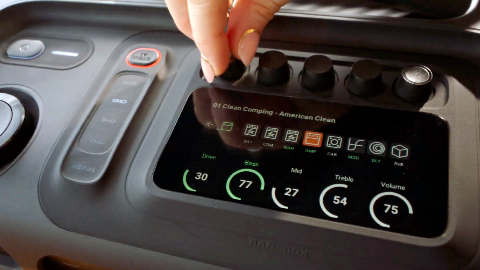 A hand adjusting knobs on the JBL BandBox Trio speaker