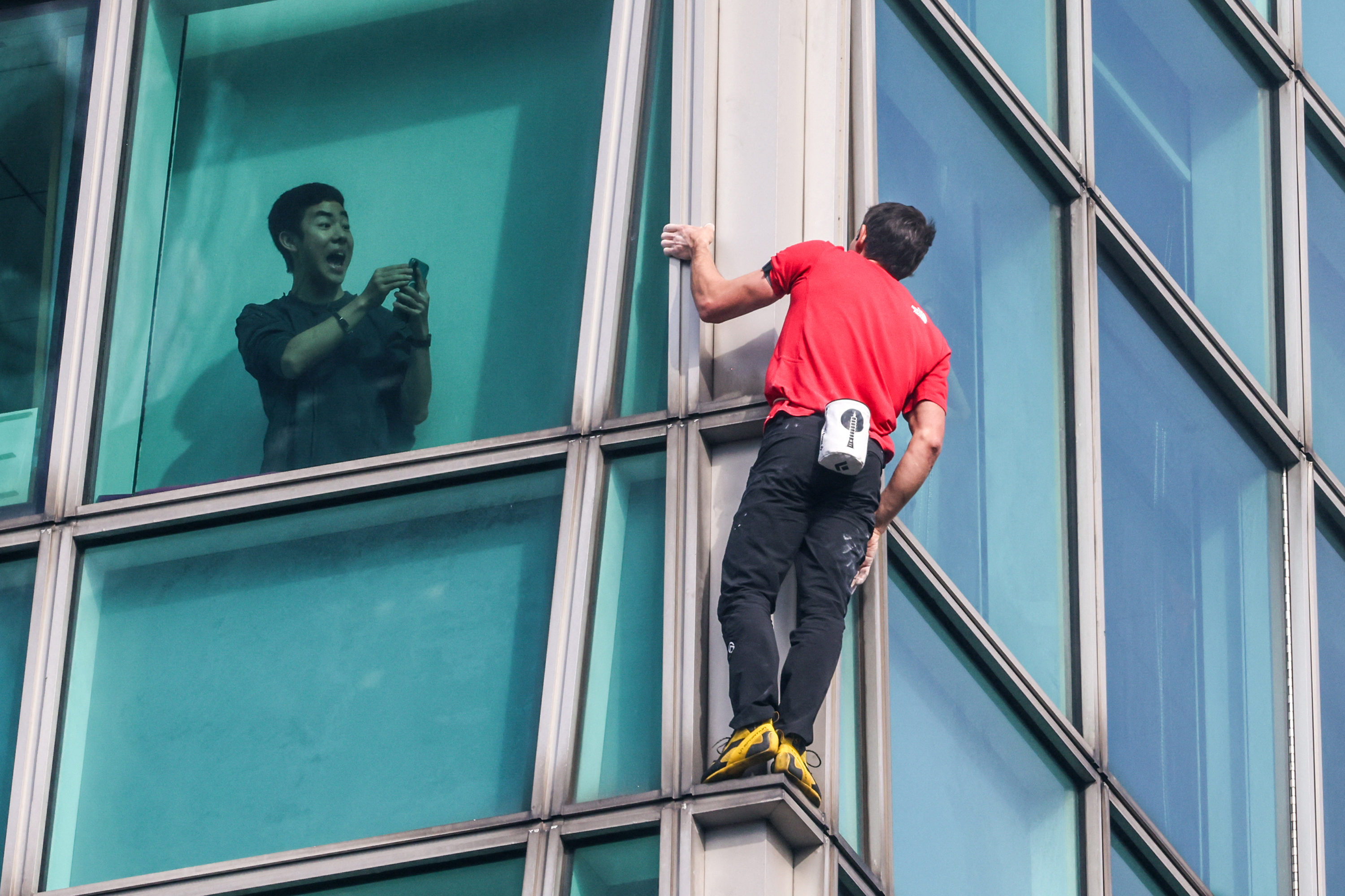 A building occupant records Honnold during his ascent. (I-Hwa Cheng/AFP via Getty Images)