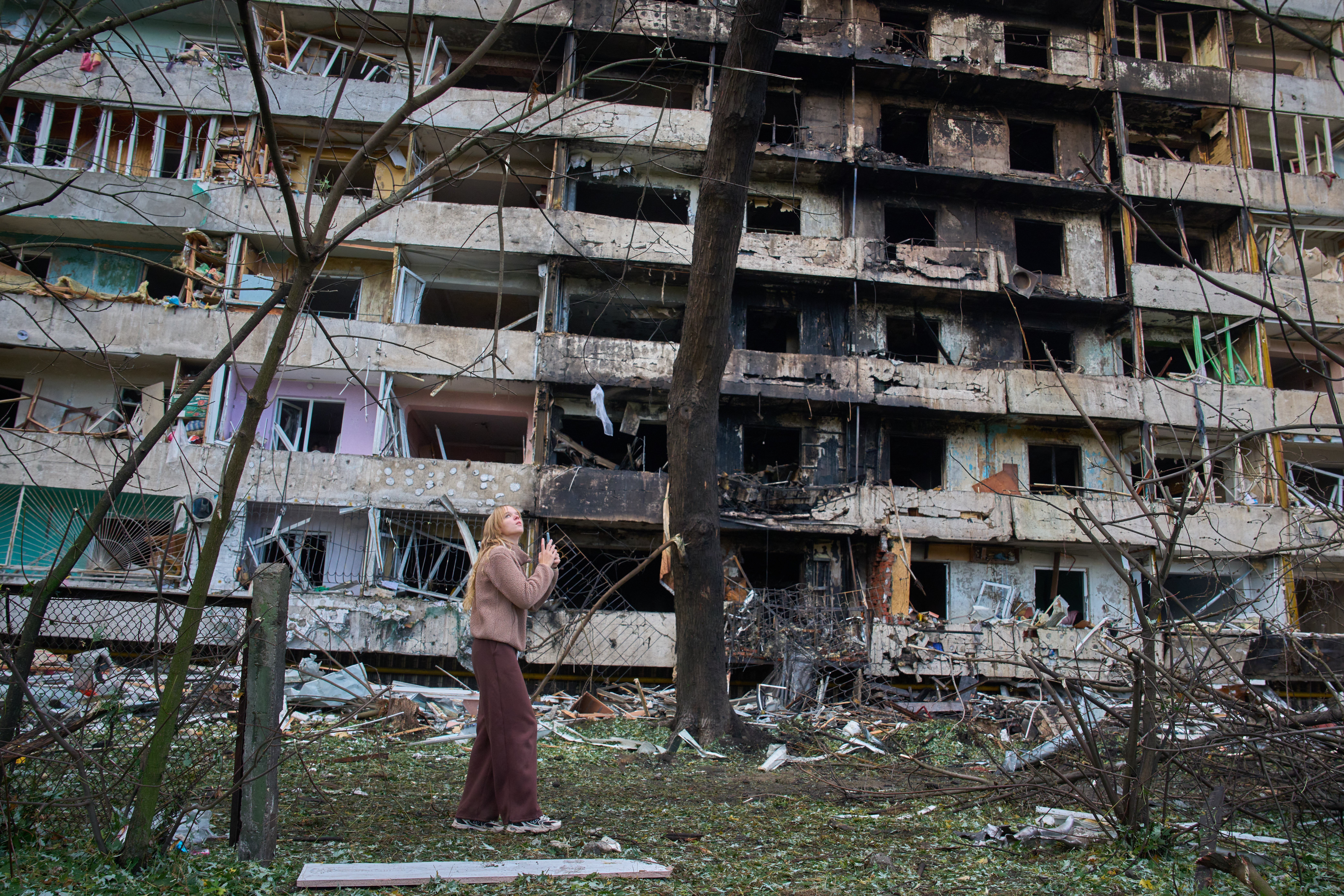 A young woman reacts as she looks at her damaged home after a Russian missile attack in Kyiv on Oct. 14.